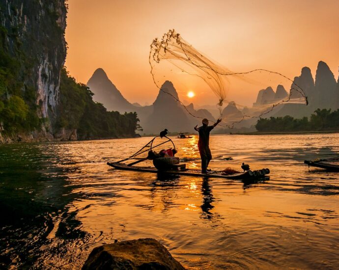 fisherman throwing fishnet on water