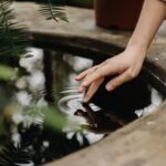 unrecognizable woman touching water in garden